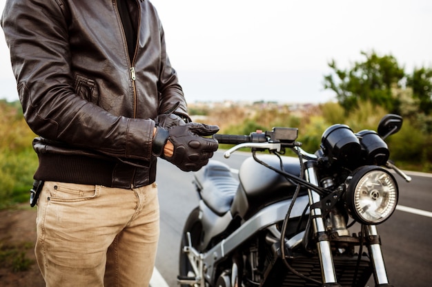 young-handsome-man-posing-near-his-motorbike-wearing-gloves_176420-2445